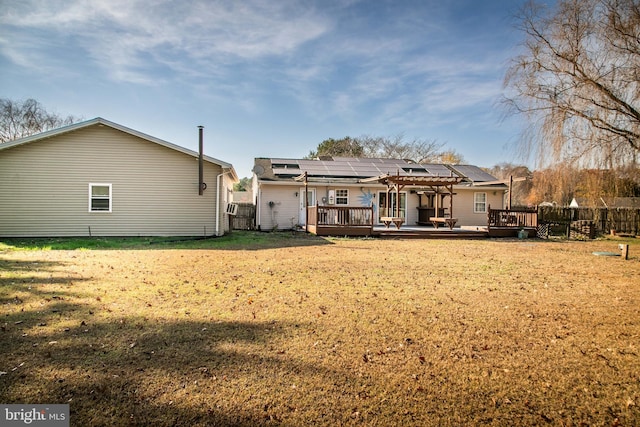 back of house featuring a lawn, solar panels, a pergola, and a wooden deck