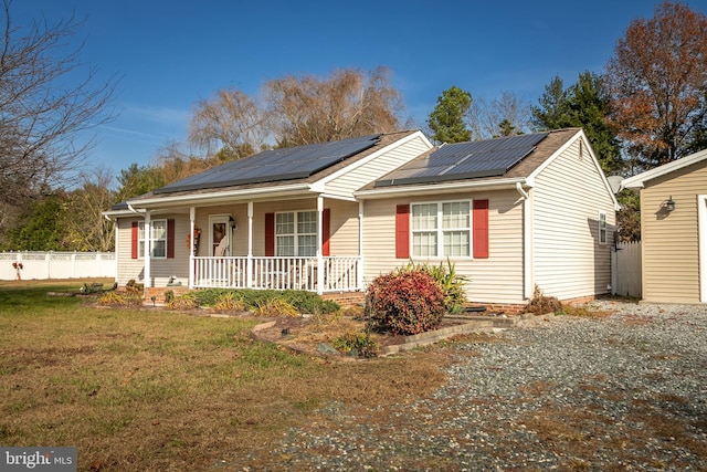 single story home with a front lawn, covered porch, and solar panels