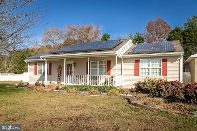 view of front facade featuring solar panels, covered porch, and a front yard