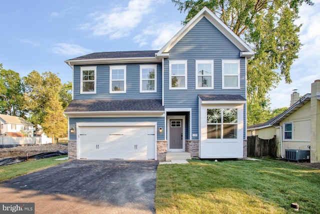 view of front of home featuring a front yard, central AC, and a garage