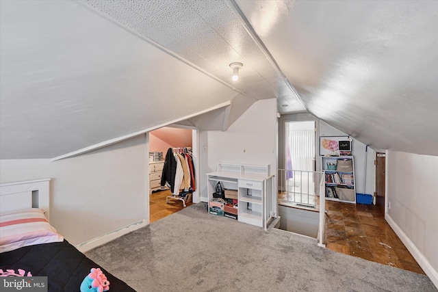 bedroom featuring a walk in closet, carpet floors, vaulted ceiling, and a closet