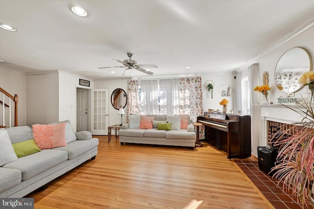 living room featuring hardwood / wood-style flooring, ceiling fan, and crown molding