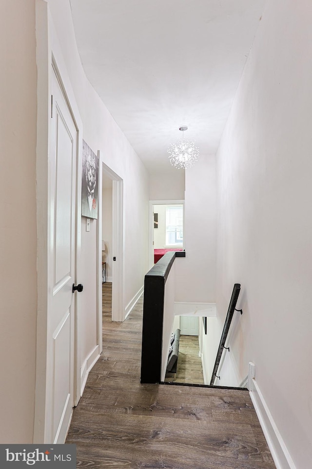 hallway featuring hardwood / wood-style flooring and an inviting chandelier