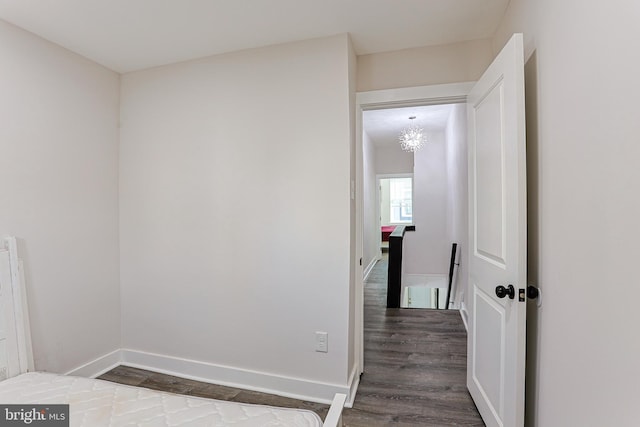 corridor featuring dark hardwood / wood-style floors and an inviting chandelier