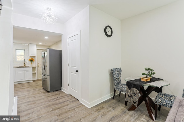 dining space with light wood-type flooring, sink, and an inviting chandelier