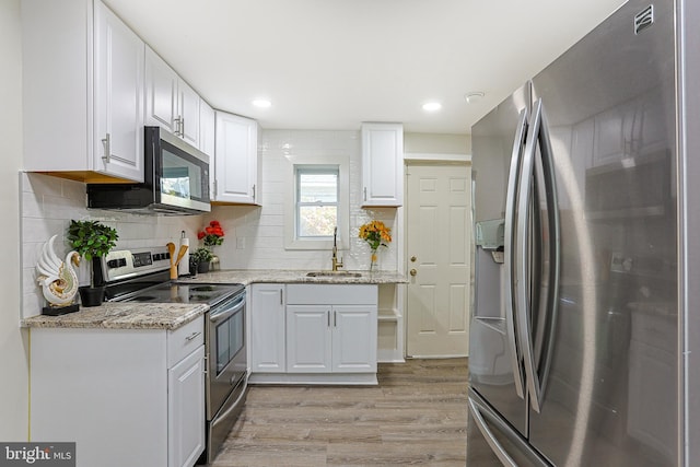 kitchen with light hardwood / wood-style floors, light stone counters, sink, white cabinetry, and appliances with stainless steel finishes