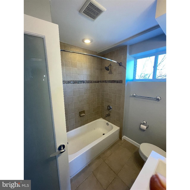 bathroom featuring toilet, tile patterned floors, and tiled shower / bath combo