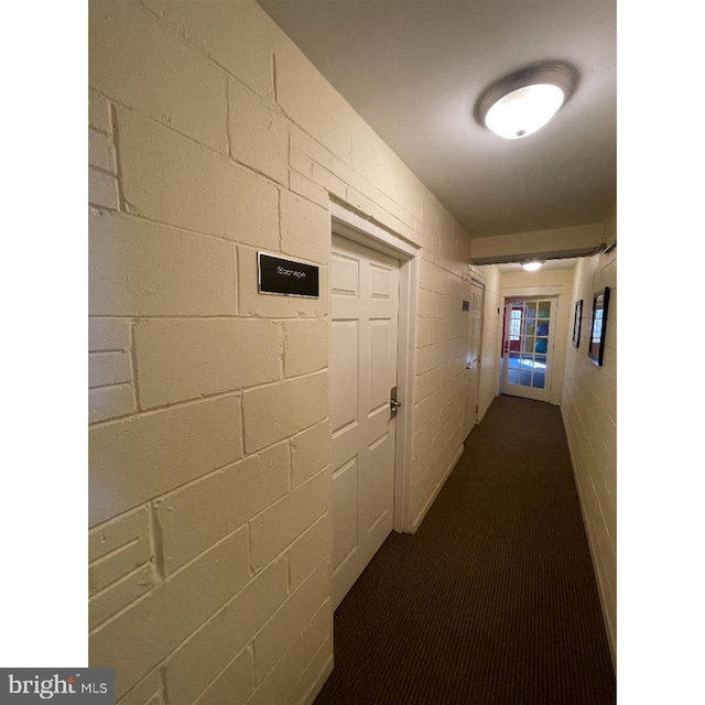 corridor with dark carpet and brick wall