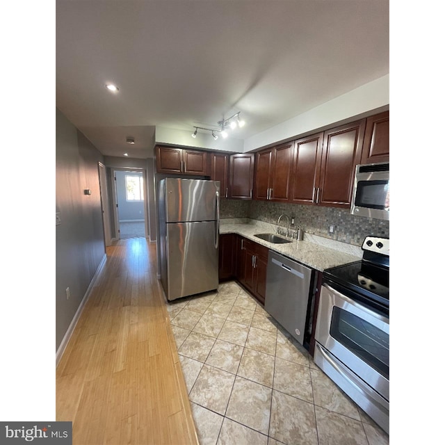 kitchen featuring backsplash, sink, light stone countertops, appliances with stainless steel finishes, and light hardwood / wood-style floors