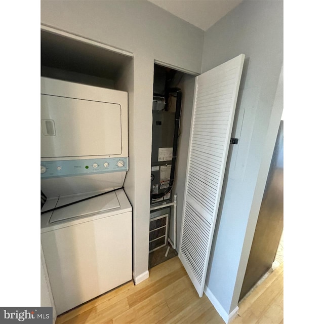 clothes washing area with stacked washer / drying machine and light hardwood / wood-style flooring