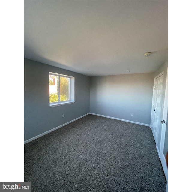 spare room featuring dark colored carpet