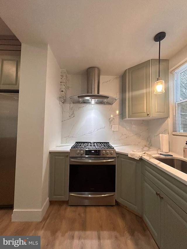 kitchen featuring gray cabinets, ventilation hood, wood-type flooring, and stainless steel gas range oven