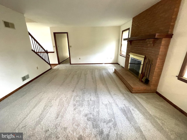 unfurnished living room featuring light colored carpet and a brick fireplace