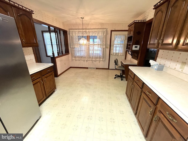 kitchen featuring built in desk, decorative light fixtures, an inviting chandelier, and stainless steel fridge