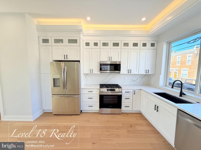 kitchen featuring white cabinets, a sink, stainless steel appliances, and light wood finished floors