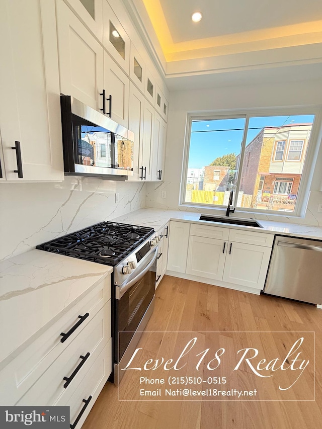 kitchen featuring white cabinets, a sink, appliances with stainless steel finishes, and decorative backsplash