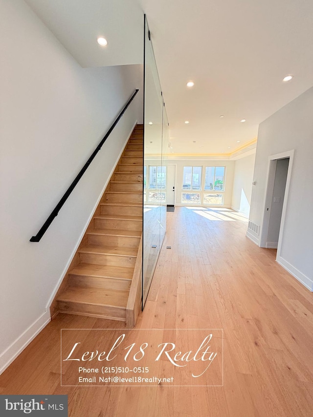 stairs with baseboards, wood finished floors, and recessed lighting