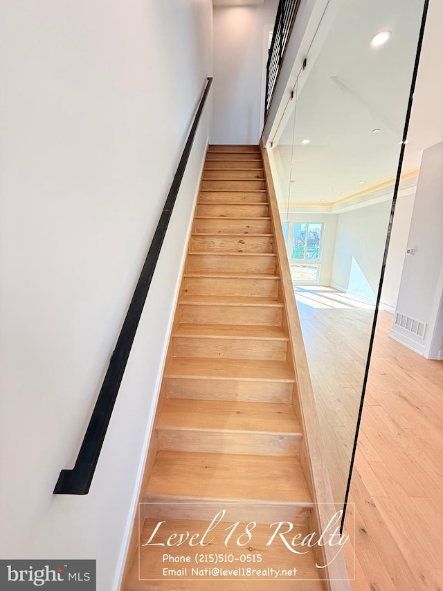 stairway with wood finished floors and recessed lighting