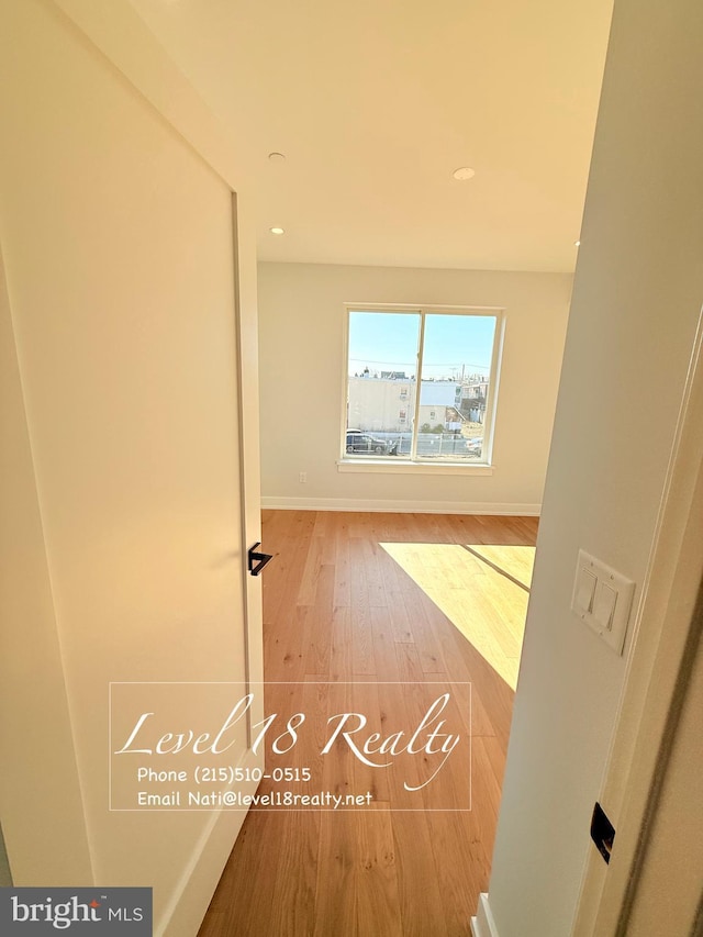 hallway featuring baseboards, wood finished floors, and recessed lighting