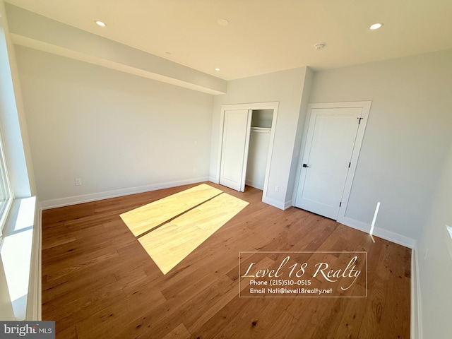 unfurnished bedroom featuring baseboards, wood finished floors, and recessed lighting
