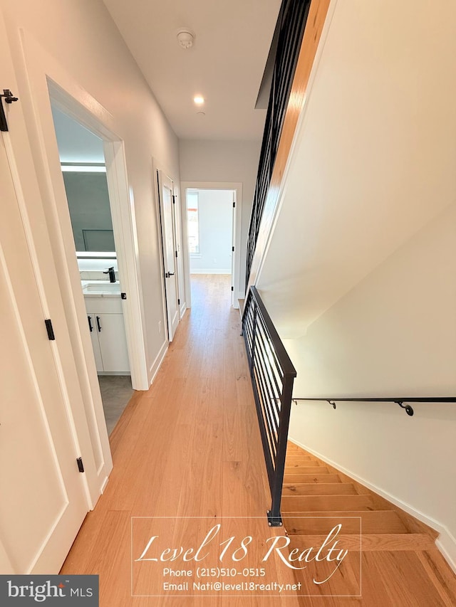 corridor with baseboards, light wood-style floors, and recessed lighting