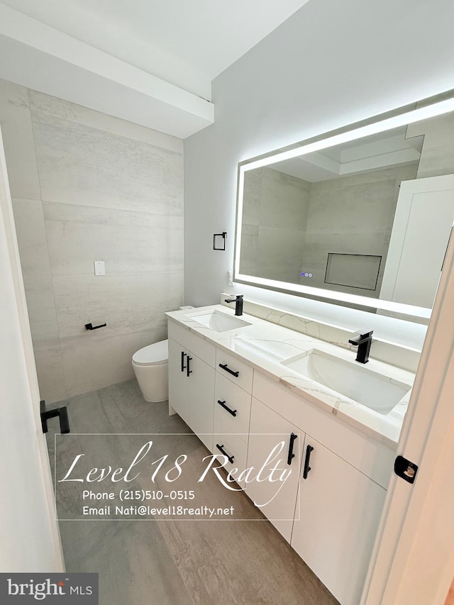 full bath featuring double vanity, a sink, toilet, and tile patterned flooring