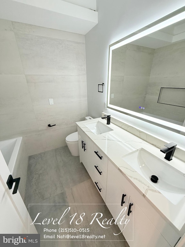 full bath featuring double vanity, a sink, toilet, and tile patterned floors