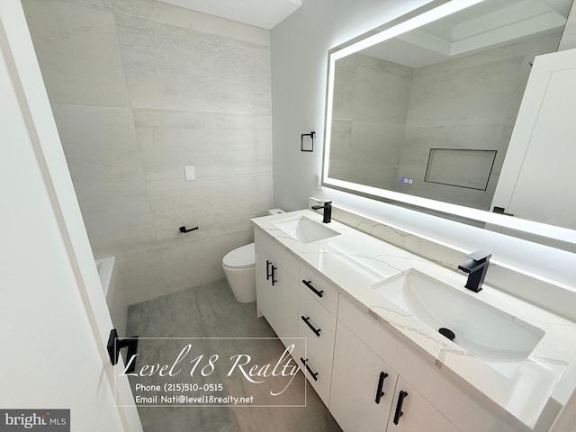 full bathroom featuring double vanity, a sink, toilet, and tile patterned floors