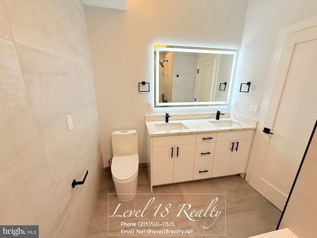 full bathroom featuring double vanity, toilet, a shower, and a sink