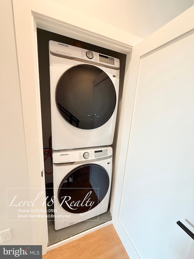 laundry area with stacked washer and dryer, wood finished floors, and laundry area