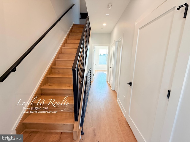 stairs with wood finished floors and recessed lighting