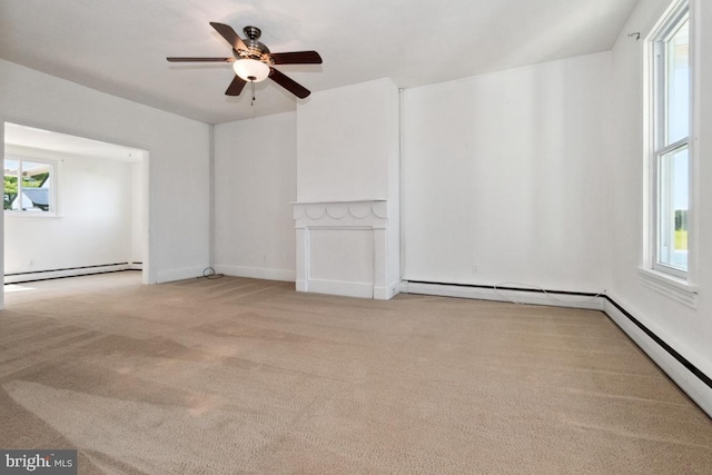 empty room featuring baseboard heating, light colored carpet, ceiling fan, and plenty of natural light