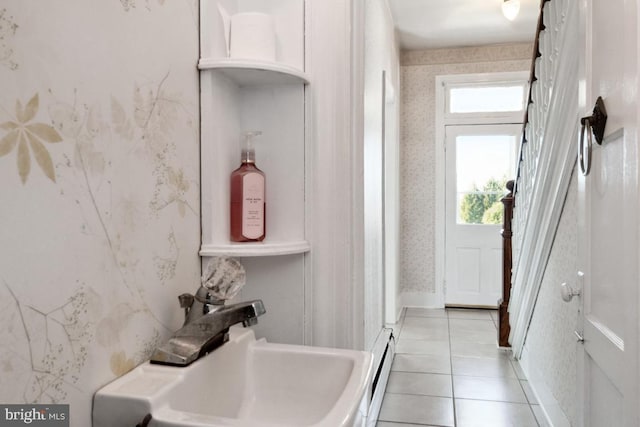 interior space with a baseboard heating unit, tile patterned flooring, and sink