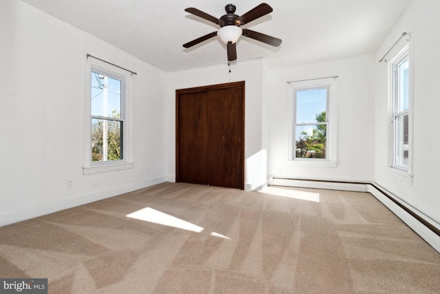 unfurnished bedroom featuring a baseboard heating unit, carpet floors, ceiling fan, and a closet