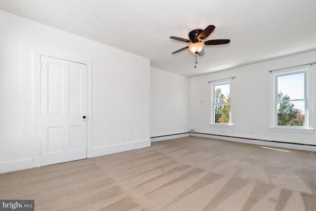 empty room with light colored carpet, ceiling fan, and a baseboard heating unit