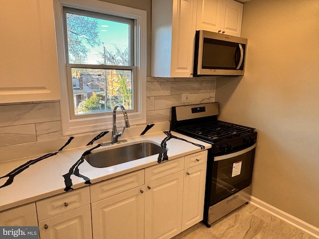 kitchen featuring white cabinets, appliances with stainless steel finishes, tasteful backsplash, and sink