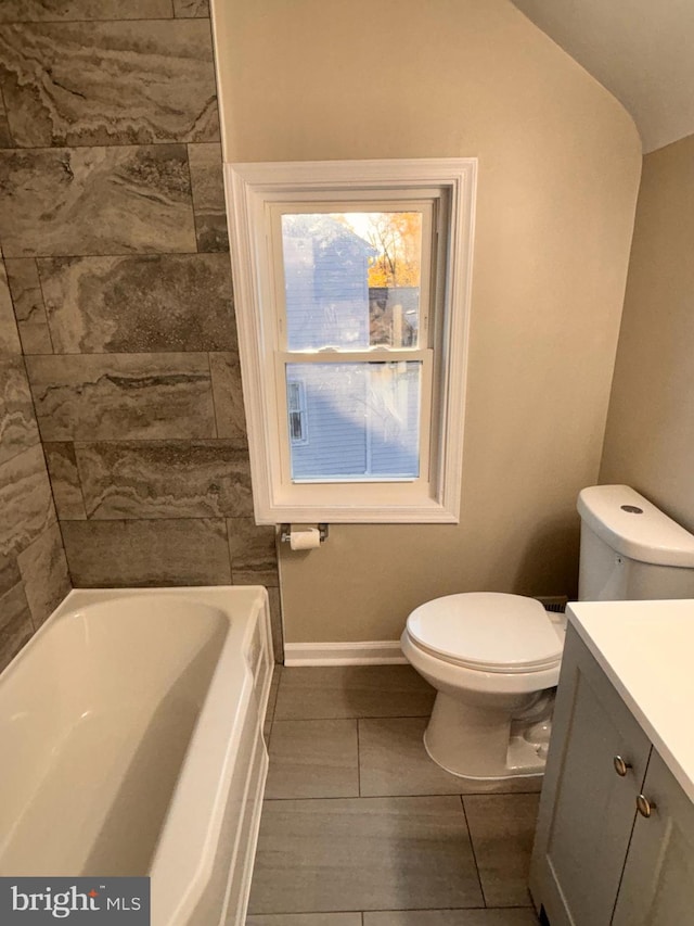 bathroom featuring a bath, tile patterned floors, lofted ceiling, toilet, and vanity