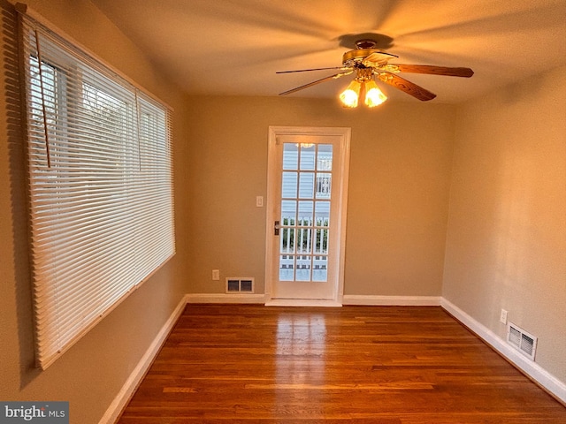 spare room featuring ceiling fan, a healthy amount of sunlight, and dark hardwood / wood-style flooring