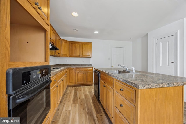 kitchen with a kitchen island with sink, light wood-type flooring, black appliances, and sink