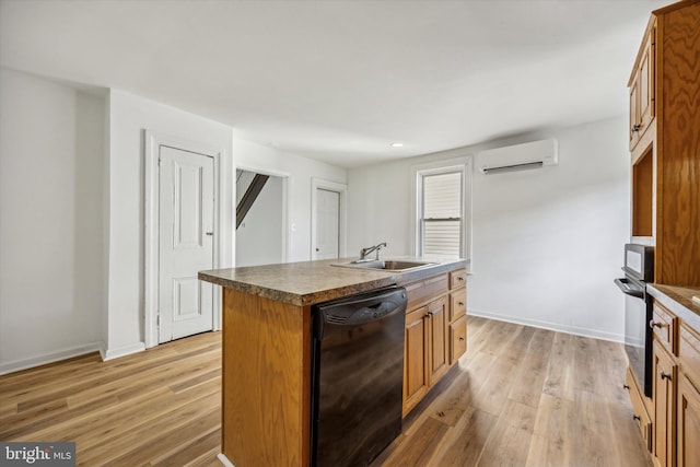 kitchen featuring a center island with sink, black appliances, sink, light hardwood / wood-style flooring, and an AC wall unit