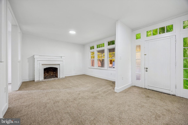 unfurnished living room featuring carpet and a brick fireplace