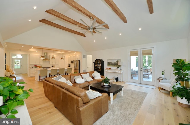 living room with plenty of natural light, beam ceiling, and light hardwood / wood-style flooring