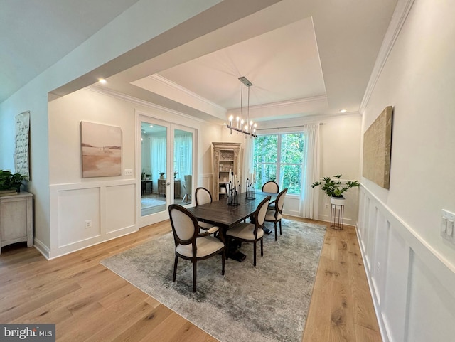 dining area featuring a raised ceiling, light hardwood / wood-style flooring, and crown molding