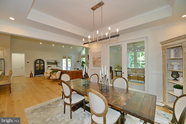 dining room featuring a raised ceiling, light hardwood / wood-style floors, and crown molding