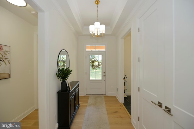 foyer with light hardwood / wood-style floors, a notable chandelier, and ornamental molding