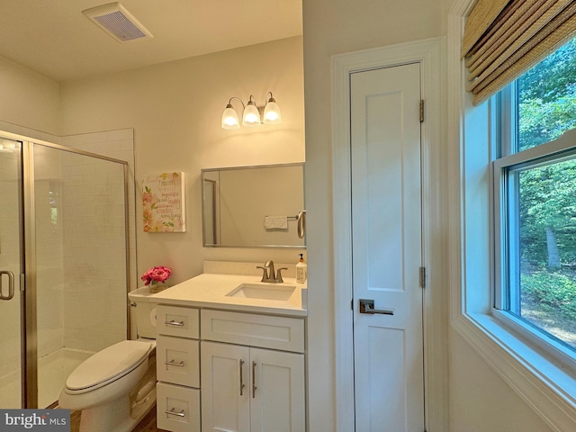 bathroom with plenty of natural light, vanity, toilet, and a shower with shower door