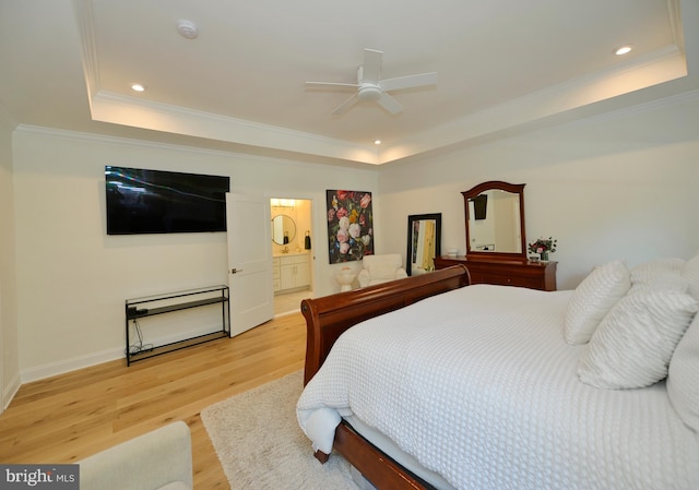 bedroom featuring connected bathroom, a raised ceiling, ceiling fan, and light hardwood / wood-style flooring