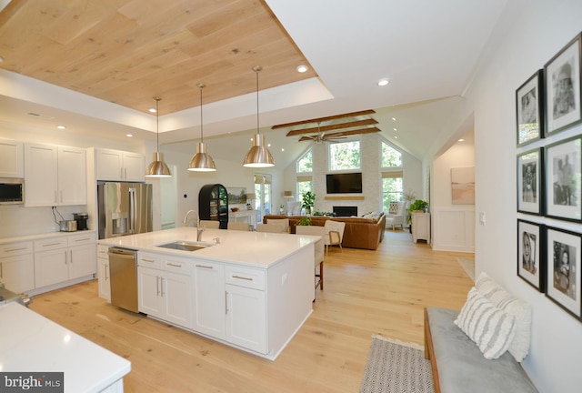 kitchen with stainless steel appliances, sink, light hardwood / wood-style flooring, white cabinets, and pendant lighting