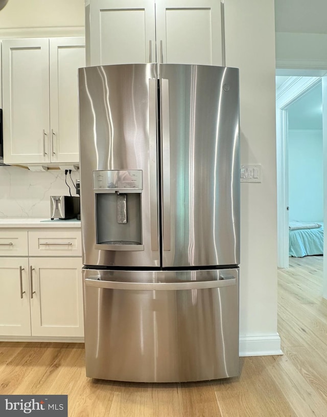 kitchen with stainless steel refrigerator with ice dispenser, white cabinetry, light hardwood / wood-style floors, and tasteful backsplash