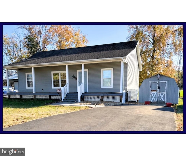 view of front of home featuring a porch, a storage unit, and a front lawn